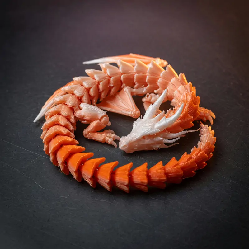 Dragão articulado laranja e branco enrolado sobre a mesa